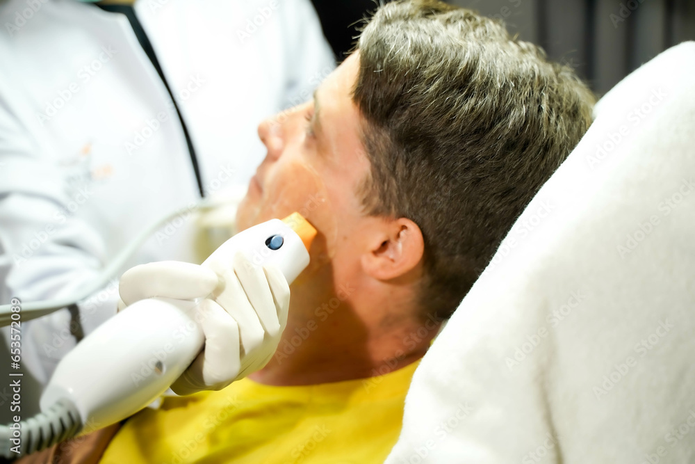 Closeup handsome man having color light therapy to stimulate facial skin wellbeing. Closeup handsome man having color light therapy to stimulate facial skin wellbeing.