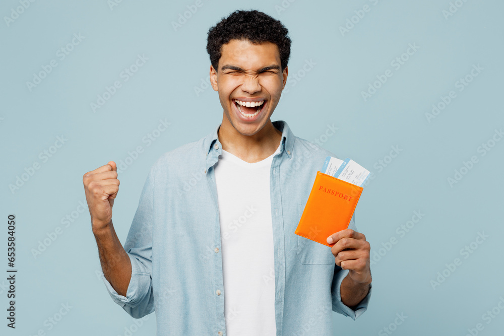 Traveler man wear casual clothes hold bag passport ticket do winner gesture isolated on plain blue background. Tourist travel abroad in free spare time rest getaway. Air flight trip journey concept. Traveler man wear casual clothes hold bag passport ticket do winner gesture isolated on plain blue background. Tourist travel abroad in free spare time rest getaway. Air flight trip journey concept.