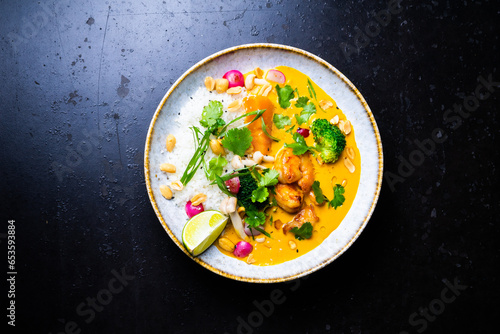 Thai chicken and peanut curry with rice, dark background, top view. Asian cuisine concept.
