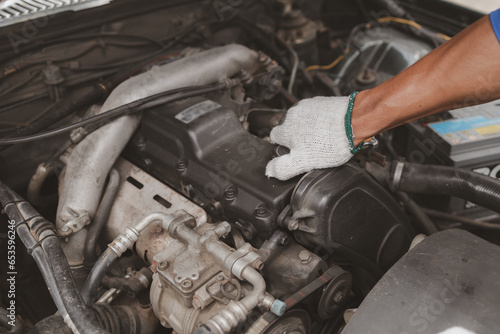 Car mechanic is inspecting the engine of a car coming in for repair at the center. Professional engine specialist, car repair, car breakdown. Car maintenance and repair concept.