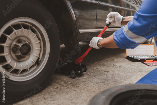 Car mechanic is inspecting tires and replacing worn tires through long hours of work, car repairs, car breakdowns, punctured tires. Concept of car tire maintenance and car repair.