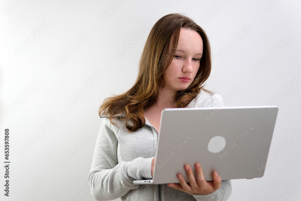 Image of a young blonde woman sitting on a white surface with a laptop in her lap. High quality photo Image of a young blonde woman sitting on a white surface with a laptop in her lap. High quality photo