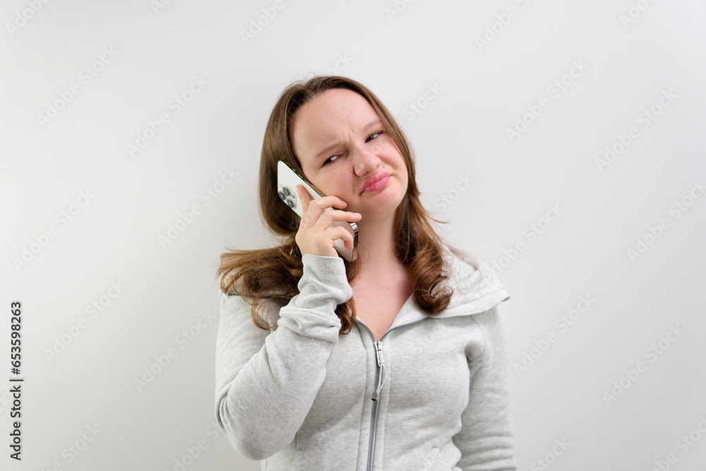 Frustrated annoyed sad woman with mobile phone standing intside. white background Frustrated annoyed sad woman with mobile phone standing intside. white background