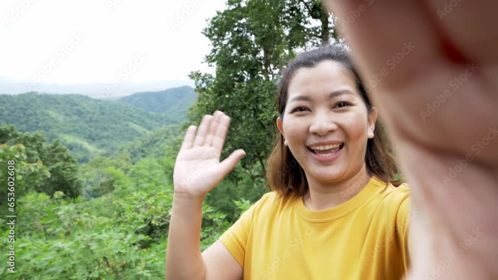 Positive female hipster waving a hand at the camera during video chat online. Smiling hiker gesturing hands. Cheerful traveler exploring nature. Positive female hipster waving a hand at the camera during video chat online. Smiling hiker gesturing hands. Cheerful traveler exploring nature.