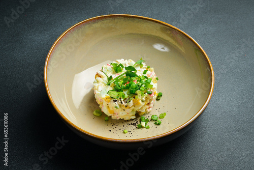 Salad with crab sticks, corn, onion and mayonnaise. On a black stone background. Free space for text.