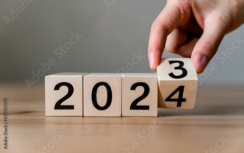Flipping of 2023 to 2024 on wooden block cube for preparation merry Christmas and happy new year change and start new business target strategy concept photo
