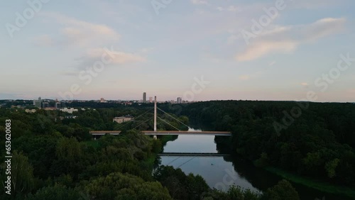 The camera flies along the river to the pedestrian bridge. Drone flying over the park