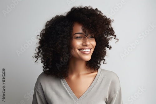 photo of a profole of a 35-year-old African woman with a fashionable haircut in a plain blouse, eye contact, smile, grey background