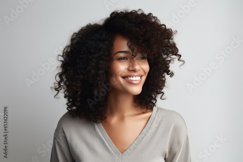 photo of a profole of a 35-year-old African woman with a fashionable haircut in a plain blouse  eye contact  smile  grey background