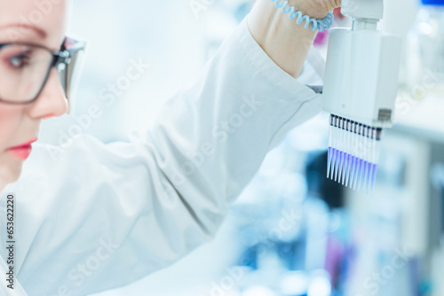 Eine Mitarbeiterin eines Labors schaut sich eine Probe in einer Pipette an, KI-generiert