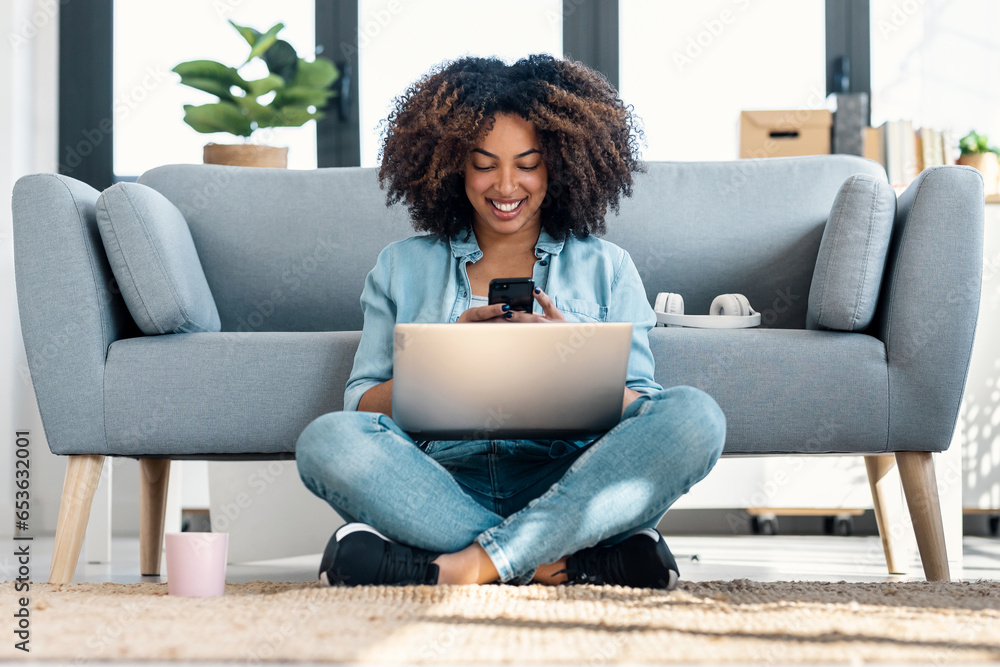 Pretty young woman using her mobile phone while working with laptop sitting on the floor at home. Pretty young woman using her mobile phone while working with laptop sitting on the floor at home.