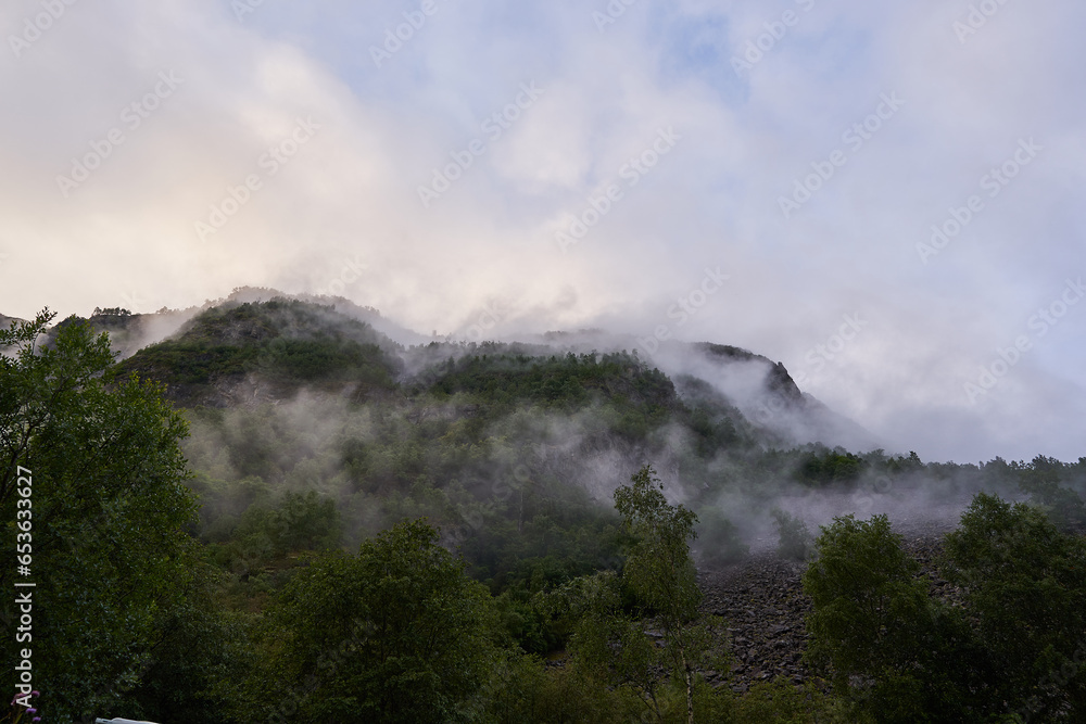 Mystic morning picture of the foggy mountains with clouds in nord Norway after heavy summer night rain. Beaufiful untouched clean european countryside, ideal to spend active summer vacations there.
