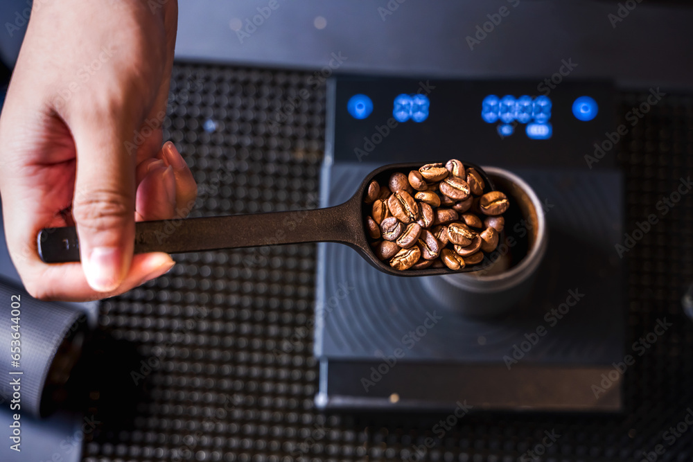 Barista coffee holding spoon of grain roasted coffee  measuring on machine in coffee shop