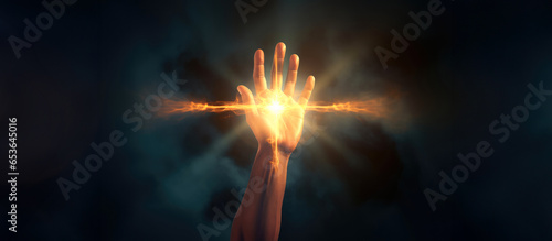 Hand holding a glowing fire cross shaped on dark background