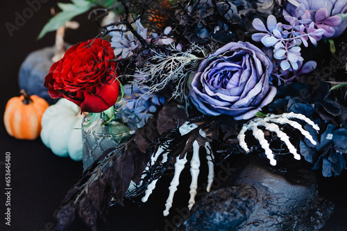 Autumn composition in dark tones with a purple rose in the centre. The theme of the holiday Halloween.