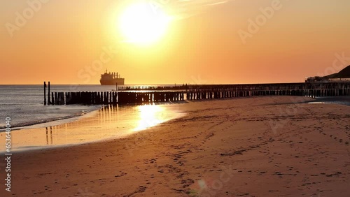In the distance large ship sits moored on an idyllic coastline. Beautiful golden hour sky photo