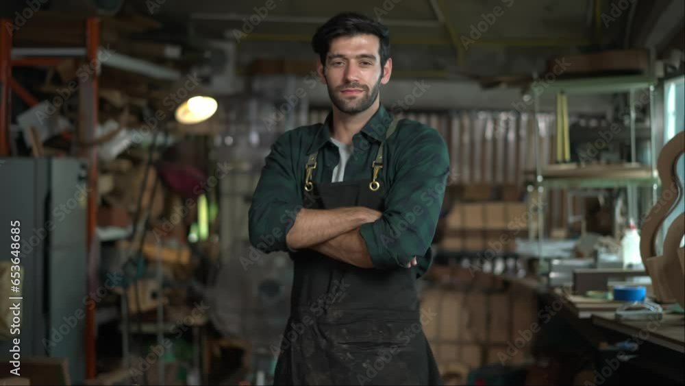Portrait of a young handsome carpenter wearing a plaid shirt and apron, smiling in his workshop. Portrait of a young handsome carpenter wearing a plaid shirt and apron, smiling in his workshop.
