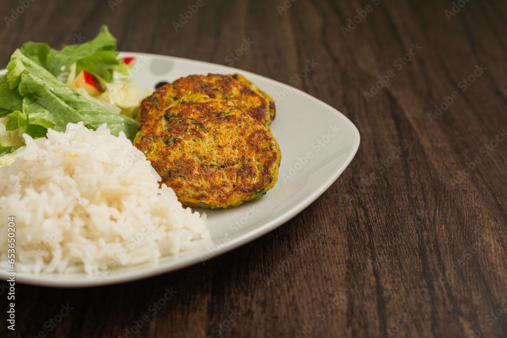 Oatmeal fritters with vegetables and white rice served on a plate on a wooden table. Healthy food. Oatmeal fritters with vegetables and white rice served on a plate on a wooden table. Healthy food.