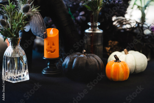Autumn composition with three pumpkins and a candle in dark colours. The theme of the holiday Halloween.