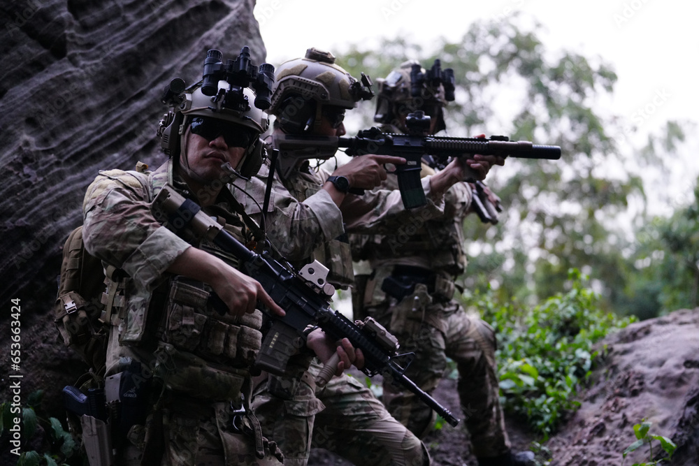 Military army soldiers tactical team, commando group moving cautiously in forest area, kneeling and looking around, covering comrades, controlling sectors. Commander showing halt or stop hand signal