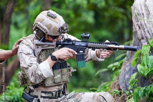 Military army soldiers tactical team, commando group moving cautiously in forest area, kneeling and looking around, covering comrades, controlling sectors. Commander showing halt or stop hand signal