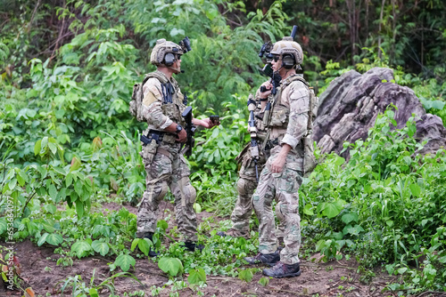 Military army soldiers tactical team, commando group moving cautiously in forest area, kneeling and looking around, covering comrades, controlling sectors. Commander showing halt or stop hand signal