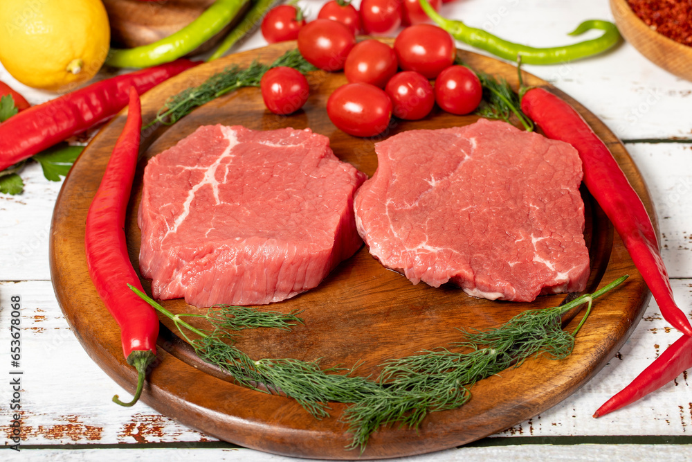 Beef round slice on wood background. Raw beef round with herbs and spices Beef round slice on wood background. Raw beef round with herbs and spices