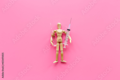 Wooden dummy man with syringe and vaccine. Medicine and healthcare concept