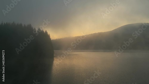 Aerial view of early morning mist floating over calm water lake. Slowly floating vapor, water evaporating over lake at down time, before sunrise 