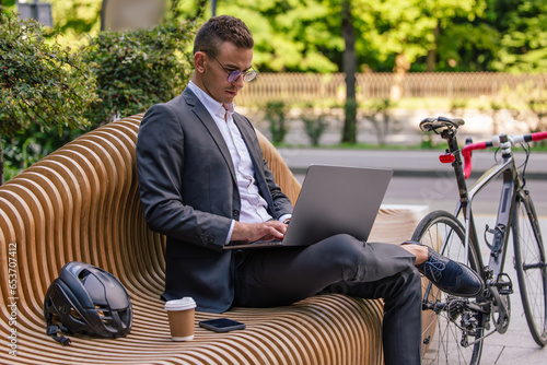 Young manager in elegant suit working on laptop and looking involved photo