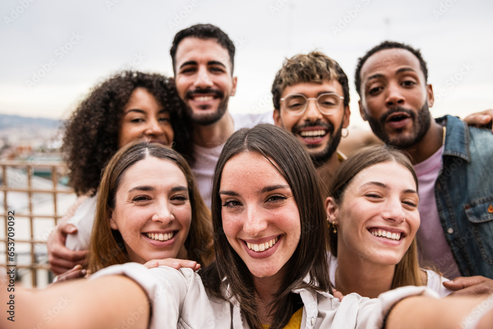 Diverse cheerful group of friends taking a selfie in a rooftop party.Multiracial young happy people smiling while taking a picture in a terrace. Diverse cheerful group of friends taking a selfie in a rooftop party.Multiracial young happy people smiling while taking a picture in a terrace.