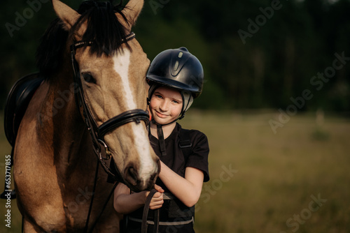 Portrait of a young jockey with a horse, horse riding training, a boy stroking a horse, a lesson for a young jockey in an equestrian school or club, pet photo