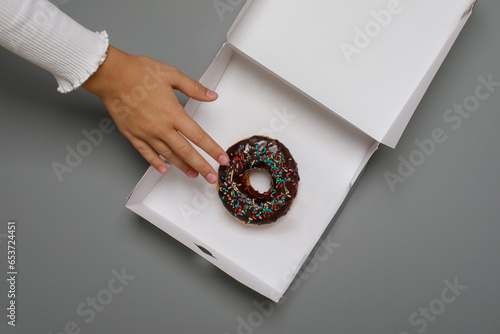 Kid hand and chocolate donut, top view