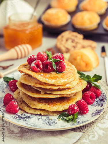 Pile of pancakes with berries and honey on plate