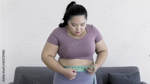 Asian woman chubby using tape measure to measure belly Feeling guilty, hopeless and stressed