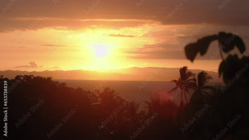 Static slow motion shot of an orange sunset from the jungle in Costa Rica. Wide shot overlooking the Pacific Ocean, with a highly contrasted sunset. Static slow motion shot of an orange sunset from the jungle in Costa Rica. Wide shot overlooking the Pacific Ocean, with a highly contrasted sunset.