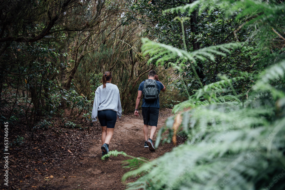 A young sporty couple walks along a path through the forest in Tenerife