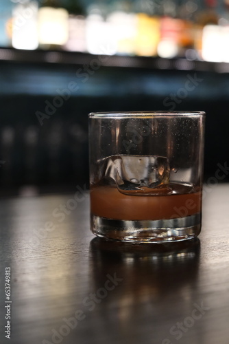 close up glass of cocktail on bar counter with colorful bokeh at dark night