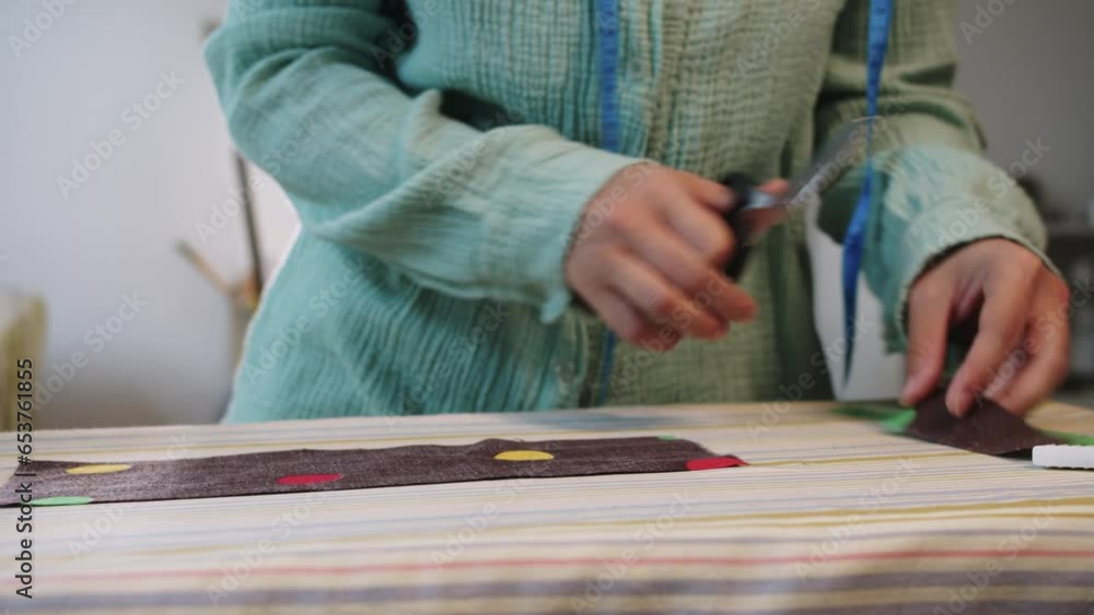 A female designer cuts off a piece from the pattern and smoothes it with an iron A female designer cuts off a piece from the pattern and smoothes it with an iron