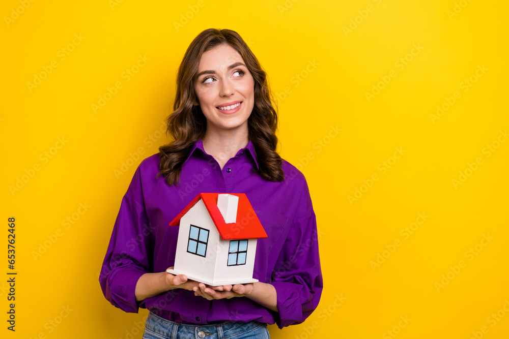 Photo of creative minded lady hold little house look empty space brainstorming isolated on yellow color background Photo of creative minded lady hold little house look empty space brainstorming isolated on yellow color background