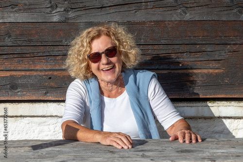 attractive senior laughing woman sitting at a rural table and enjoys life