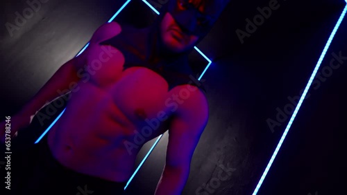 sexy man with naked muscular torso and black latex mask on head, portrait in red lights, role play photo