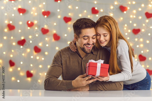 Thank you, love. Young couple celebrating their special date. Woman giving present to her boyfriend on anniversary or St Valentines Day. Happy man thanking his girlfriend for cute Valentine gift photo