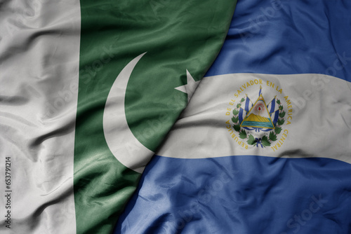 big waving realistic national colorful flag of pakistan and national flag of el salvador .