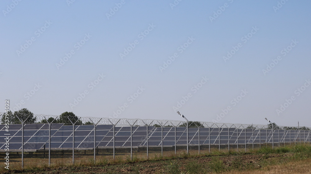 a complex of solar panels standing on a country field behind a wire fence, solar panels in operation, modern equipment used in the field of energy saving and alternative energy a complex of solar panels standing on a country field behind a wire fence, solar panels in operation, modern equipment used in the field of energy saving and alternative energy