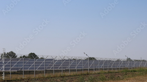 Wallpaper Mural a complex of solar panels standing on a country field behind a wire fence, solar panels in operation, modern equipment used in the field of energy saving and alternative energy Torontodigital.ca