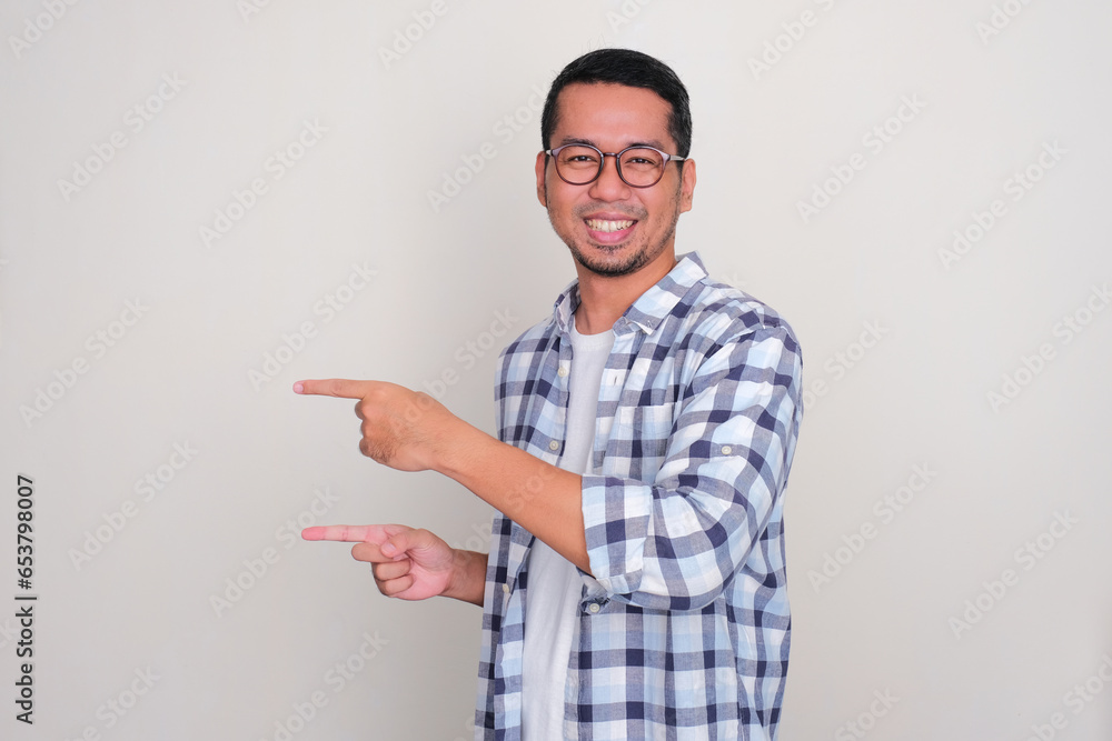 Adult Asian man smiling happy with both hands pointing to the right side Adult Asian man smiling happy with both hands pointing to the right side