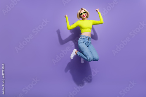 Photo of charming overjoyed girl wear trendy bright clothes celebrate success jump empty space isolated on purple color background