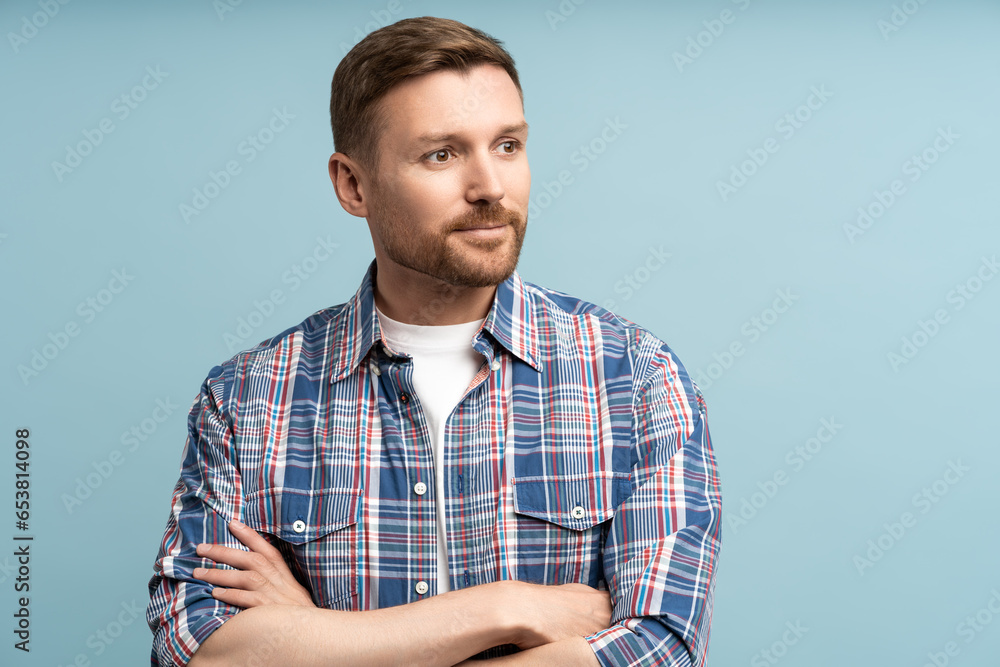 Pensive man isolated on studio wall crossed arms. Satisfied focused guy