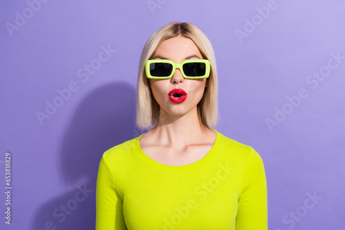 Portrait of impressed ecstatic woman with bob hairdo dressed yellow top in sunglass staring open mouth isolated on purple color background